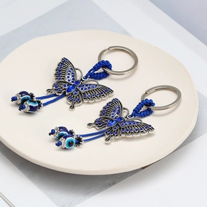 Butterfly keychain with blue rhinestones and evil eye beads in a ceramic tray