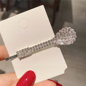 Détail d'une pince à cheveux en forme de cuillère en métal argenté et strass brillants