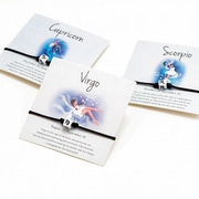 Detailed view of woven Capricorn Virgo and Scorpio zodiac bracelets on cards
