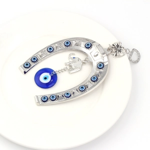 Detailed view of silver evil eye horseshoe pendant with blue glass beads and elephant charm