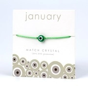 Detail view of the green woven Evil Eye bracelet on its white January series display card