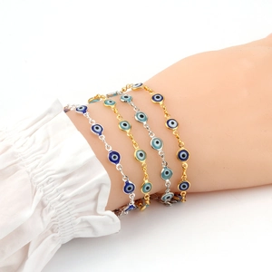 Détail de bracelets mauvais œil dorés et argentés portés sur un poignet en dentelle