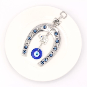 Detailed close-up of a horseshoe and elephant hanging ornament with blue evil eyes