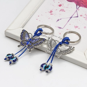 Detail of butterfly keychain with blue rhinestones, evil eye beads and woven rope