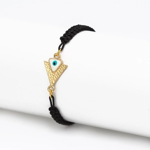 Détail du porte-bonheur œil grec sur bracelet tressé noir avec triangle doré martelé