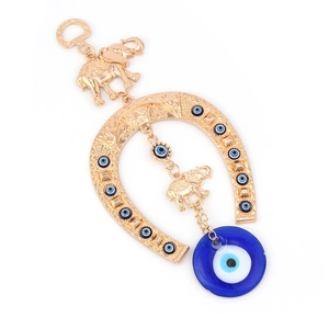 Detail of golden horseshoe pendant with blue evil eye beads and lucky elephant charms