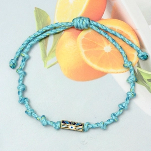Detail of hand-woven sky blue cord bracelet featuring a gold evil eye charm