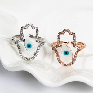 Detail of silver and rose gold Hamsa Hand open rings with evil eye and white zircon