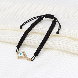 Vue macro du bracelet tressé noir avec œil protecteur, nœud ajustable et pendentif doré