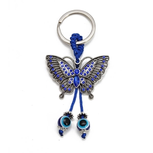 Elegant butterfly keychain with blue rhinestones and evil eye lucky charms on white background