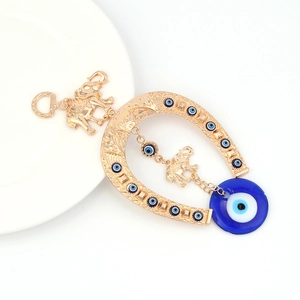 Macro detail of metal horseshoe pendant with evil eye charms and golden elephant accents