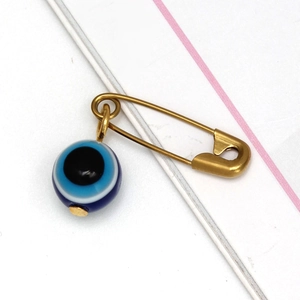 Primer plano del imperdible dorado con colgante de cuenta azul del ojo del mal