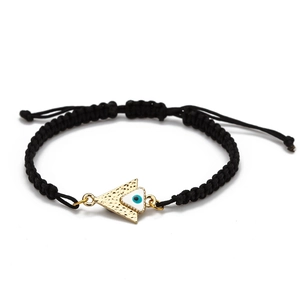 Gros plan du bracelet en corde noire tressée avec pendentif œil maléfique doré texturé