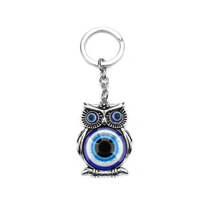 Detail of silver owl keychain with blue glass evil eye charms and polished metal ring