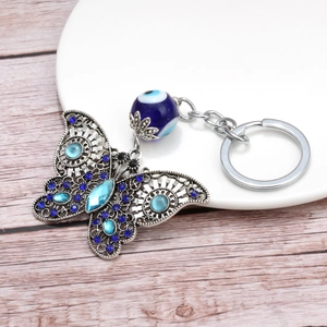 Elegant butterfly evil eye keychain featuring blue rhinestones on a white ceramic plate
