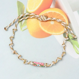 Macro detail of hand-woven cord bracelet with colorful enamel Evil Eye charm and gold thread