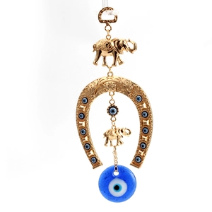 Detailed close-up of golden elephant and evil eye charms on a lucky horseshoe wall hanging