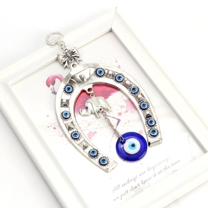 Detailed view of silver horseshoe wall decor with blue evil eye beads and small elephant pendant