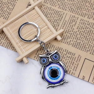 Silver owl evil eye keychain with blue Nazar charm on a vintage decorative background