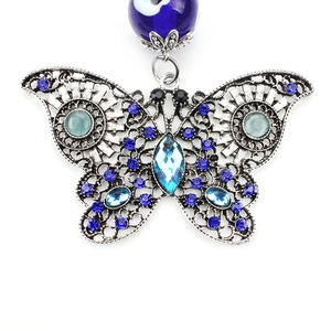 Macro shot of silver butterfly keychain with blue rhinestones and Evil Eye bead detail