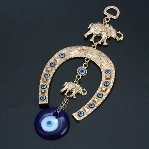 Macro detail of golden horseshoe evil eye hanging ornament with elephant charms