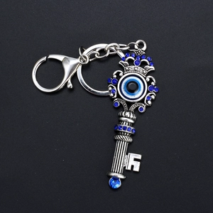 Antique silver evil eye key shaped keychain with blue rhinestones on black background