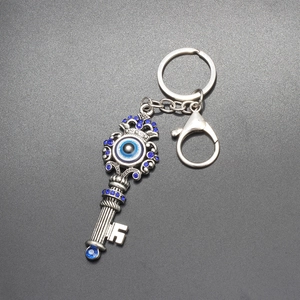 Detailed close-up of retro silver key-shaped keychain with Evil Eye blue rhinestones