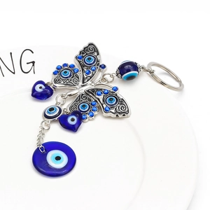 Detail of blue evil eye butterfly keychain with rhinestones on a white ceramic plate