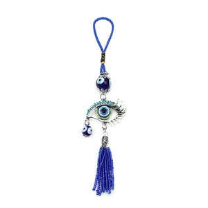 Close-up of Turkish Evil Eye pendant with silver eyelash frame and blue bead tassels