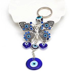 Detail of butterfly keychain with blue evil eye charms on white ceramic dish