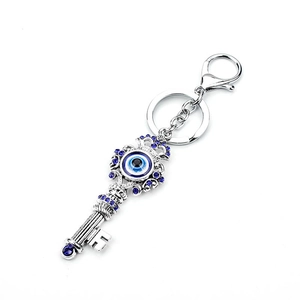 Detail of silver key-shaped evil eye keychain with blue rhinestones and lobster clasp