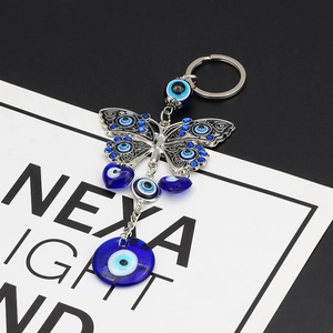 Detail of butterfly keychain with blue evil eye glass charms and silver metal filigree