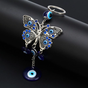 Detail of butterfly keychain featuring evil eye charms and intricate silver alloy texture