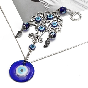 Detail showing Evil Eye Tree of Life pendant with blue glass beads on a white desk