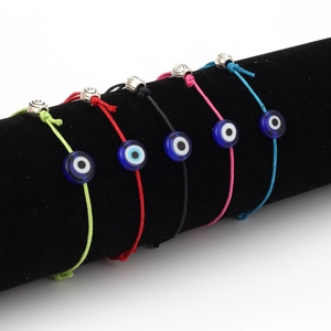 Detail van vijf kleuren gevlochten Evil Eye-armbanden op een zwarte fluwelen display