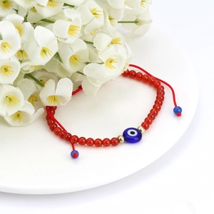 Handmade red beaded bracelet with blue Evil Eye charm and golden accents for protection