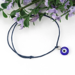 Detail van blauwe gevlochten evil eye armband met schuifknoop en glazen bedeltje