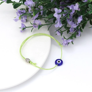 Handgemaakt lichtgroen armbandje met boze oog en zilveren spiraal kraal op bord
