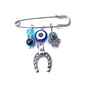 Dettaglio spilla in argento con mano di Fatima e ciondoli portafortuna Evil Eye