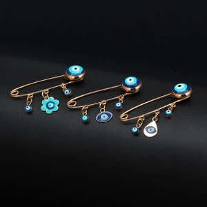 Macro view of gold-plated safety pin brooches featuring blue enamel Evil Eye charms