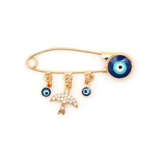 Detail of a golden safety pin brooch featuring blue evil eye charms and a sparkling swallow