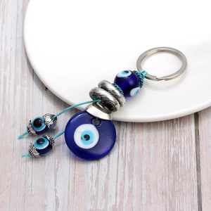 Porte-clés œil bleu en verre avec anneau argenté sur une assiette en céramique blanche