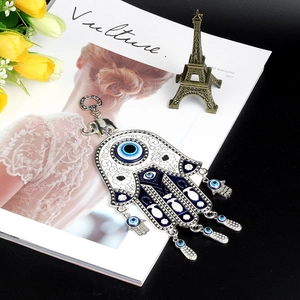 Detail of Hamsa Hand and Evil Eye hanging ornament with elephant hook on a magazine