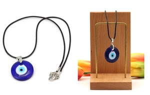Detail showing the deep blue glass Evil Eye pendant with a black woven cord necklace