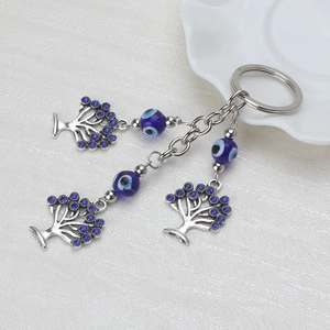 Detail of silver Tree of Life charms and blue Evil Eye glass beads on a keychain