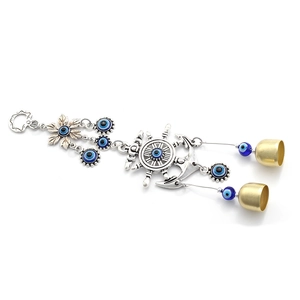 Macro shot of anchor and rudder metal pendant with blue evil eye beads and small bells