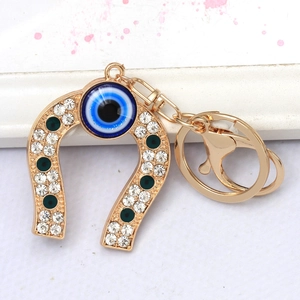 Detailed view of golden horseshoe keychain with evil eye charm and sparkling crystals