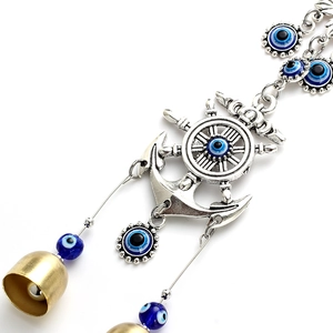 Macro detail of nautical anchor and evil eye charm with two small golden bells