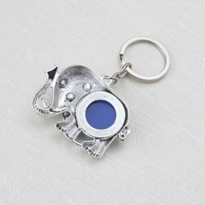 Vue détaillée d'un porte-clés éléphant en argent avec pierre d'œil bleu sur surface texturée