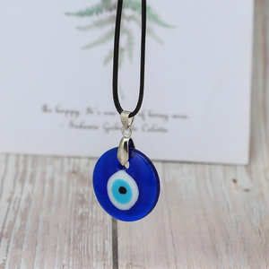 Blue glass evil eye pendant necklace with black cord and silver clasp on wood background